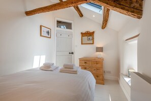 Ein Schlafzimmer mit einem Bett, einer Holzkommode, einer Tür und einem Oberlicht.