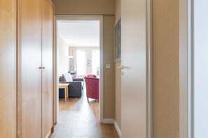 A hallway leading to a living area with a sofa, chair, and a red piece of furniture. - Ferienwohnung mit Badewanne in Sellin (Sellin)