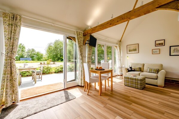 A room with a wooden floor, a dining table with chairs, a sofa, and a painting on the wall.
