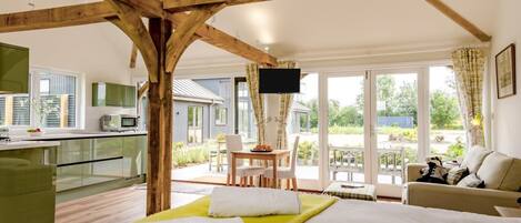 Un dormitorio con cama, televisor, zona de comedor y vistas al exterior.