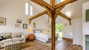 Ein Schlafzimmer mit Holzbalkendecke, einem Bett, einem Nachttisch, einer Couch, einer Bank und gerahmten Bildern an der Wand.