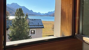 Ein Fenster mit Blick auf einen See, Berge und ein Haus.