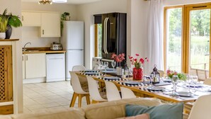 Eine moderne Küche mit weißen Schränken, einem schwarzen Kühlschrank und einem Essbereich mit Tisch für vier Personen.