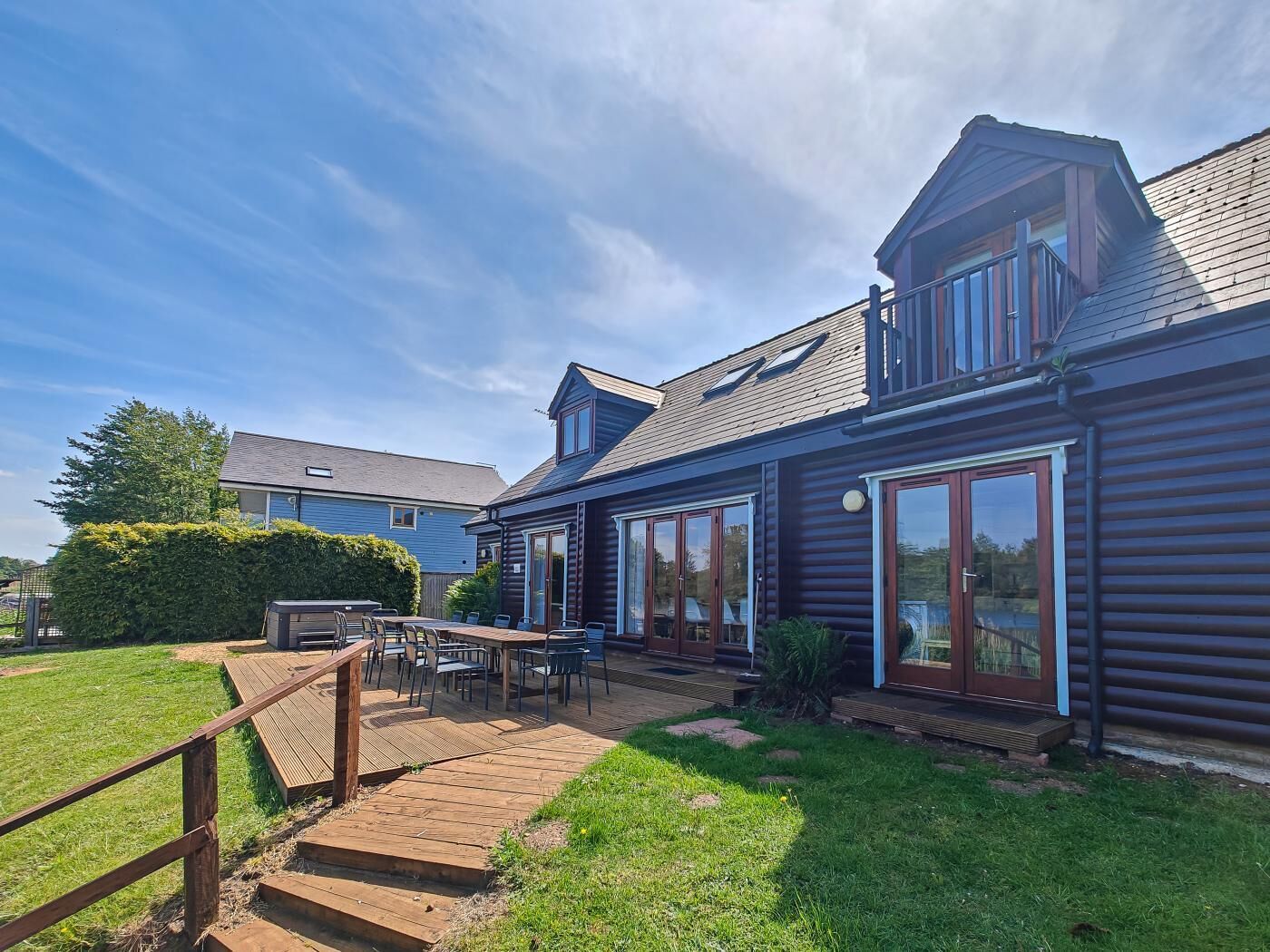 A wooden cabin with a deck, large windows, and a clear sky.
