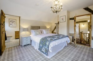 Ein Schlafzimmer mit einem Bett, Nachttischen, einer Chandelier, einer Treppe und einem Spiegel.