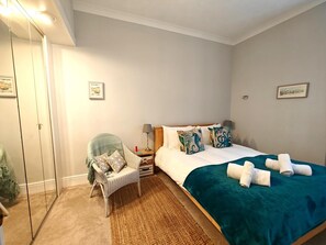 A bedroom with a bed, a chair, a nightstand, a lamp, and a mirror. - 2 Bed in Weymouth (oc-s42747) (Weymouth)