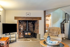 A living room with a brick fireplace, a television, a sofa, and a coffee table. - 4 Bed in Shorwell (oc-w42664) (Shorwell)