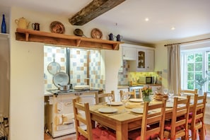 A kitchen with a dining table set for six, a microwave, and a window with curtains. - 4 Bed in Shorwell (oc-w42664) (Shorwell)