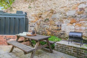 A stone wall, a wooden picnic table with a basket, a kettle, and a grill. - 4 Bed in Shorwell (oc-w42664) (Shorwell)