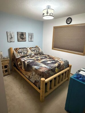 A bedroom with a wooden bed, a ceiling light fixture, a window with blinds, and wall art. - Secluded Woodland Retreat for 6 Near Wisconsin Dells, Lakes & ATV Trails (New Lisbon)