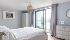 Une chambre à coucher comprenant un lit, une armoire, une commode, un miroir et un balcon avec vue.