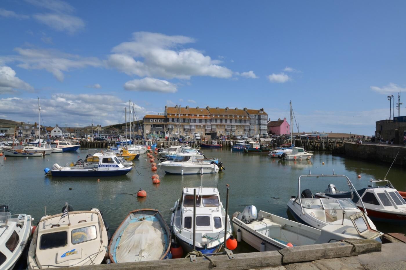 A marina with boats docked, a building with a red roof, and a clear sky.