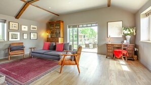 Ein großzügiges Wohnzimmer mit einer Couch, Sesseln, einem Teppich, einer Kommode und Kunstwerken an den Wänden.
