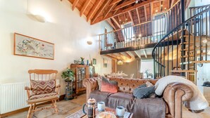 Un'ampia zona giorno con soffitto alto, una scala e una sala da pranzo.