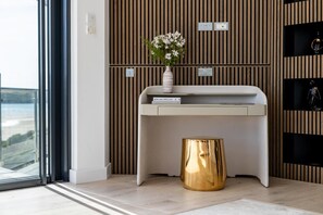 Ein moderner Raum mit einer Wand aus Holzleisten, einem weißen Konsolentisch, einem goldenen Akzent und einer Vase mit Blumen.