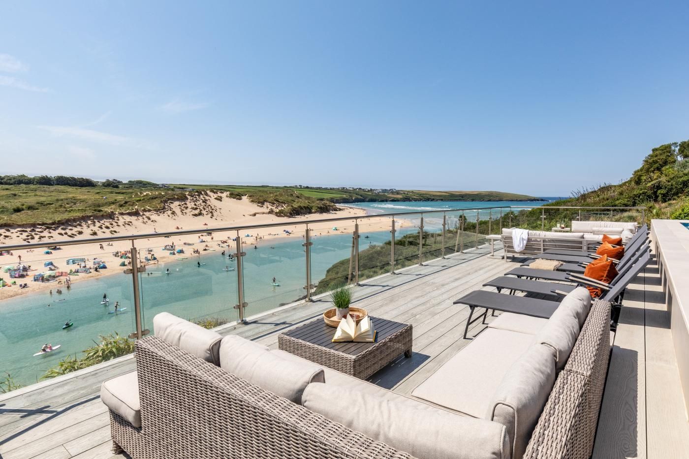 Une terrasse sur le toit offrant une vue sur une plage et la mer, aménagée avec des canapés et une table.