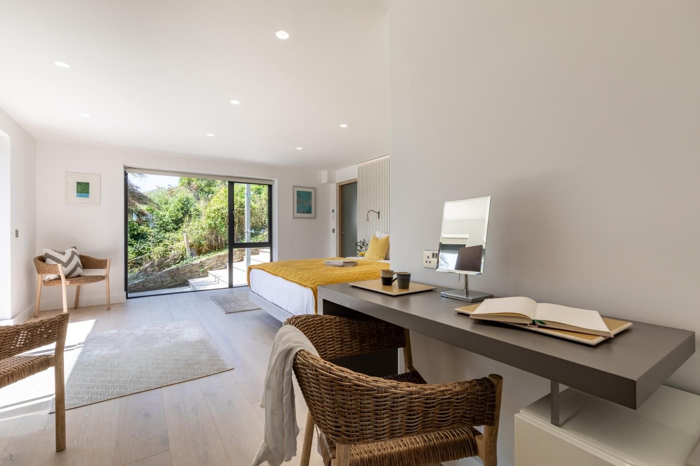 Une chambre moderne avec un grand lit, un bureau et une vue sur la verdure environnante.