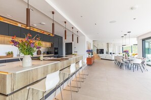 Eine moderne Küche mit einer zentralen Kochinsel, einer Bar und einem Essbereich mit Blick.