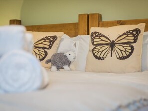 Ein Bett mit weißer Bettwäsche, einem Holz-Kopfteil und zwei Kissen mit Schmetterlingsmuster.