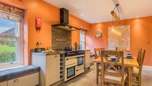 Eine Küche mit Steinrückwand, Holzschränken, einem eingebauten Ofen und einem Essbereich mit Holztisch und -stühlen.