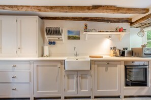 A kitchen with white cabinetry, a sink, a stove, and various kitchen utensils. - 2 Bed in Yealmpton (oc-o42800) (Yealmpton)
