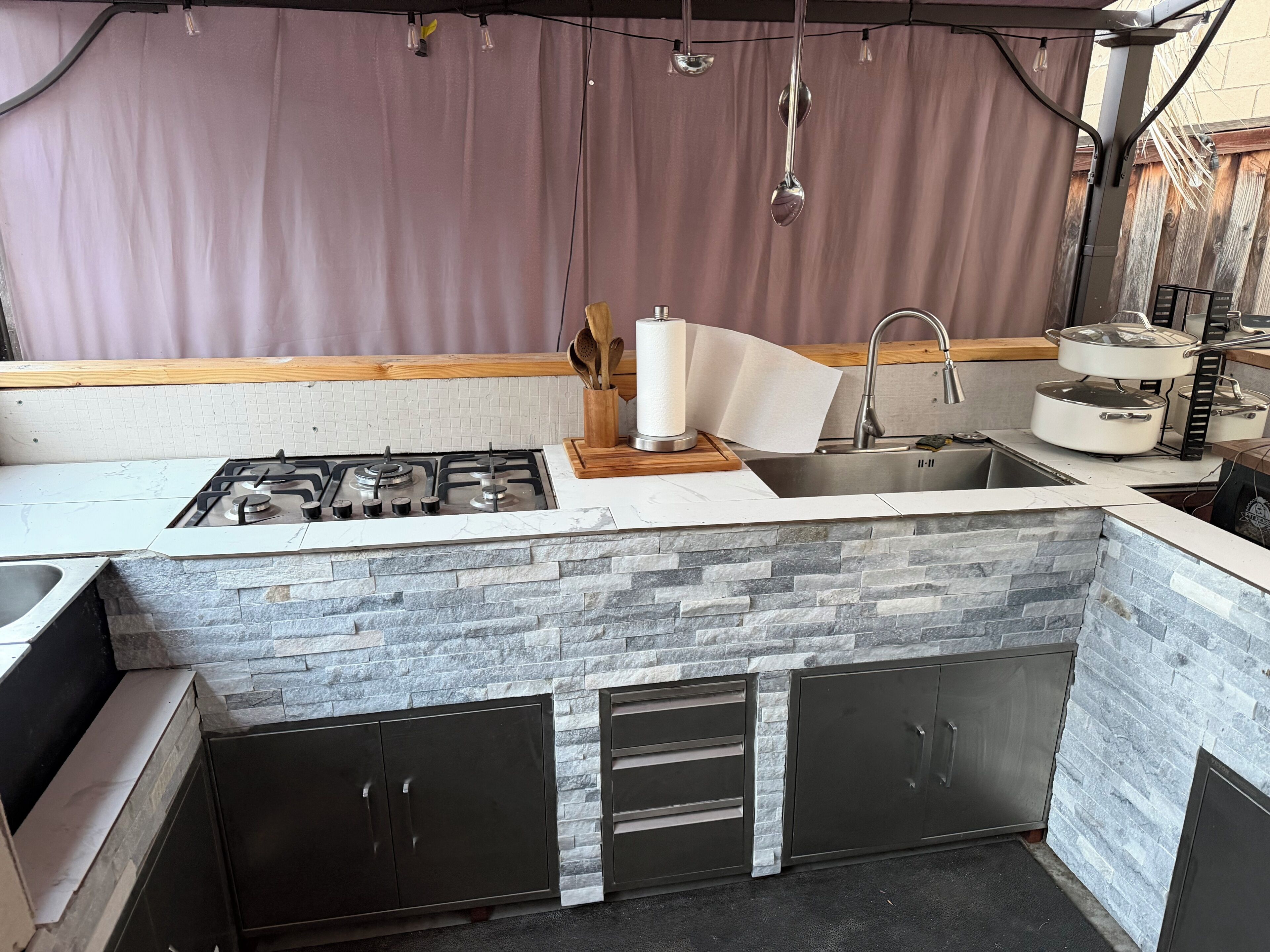 A kitchen with a gas stove, a sink, and a stone backsplash.