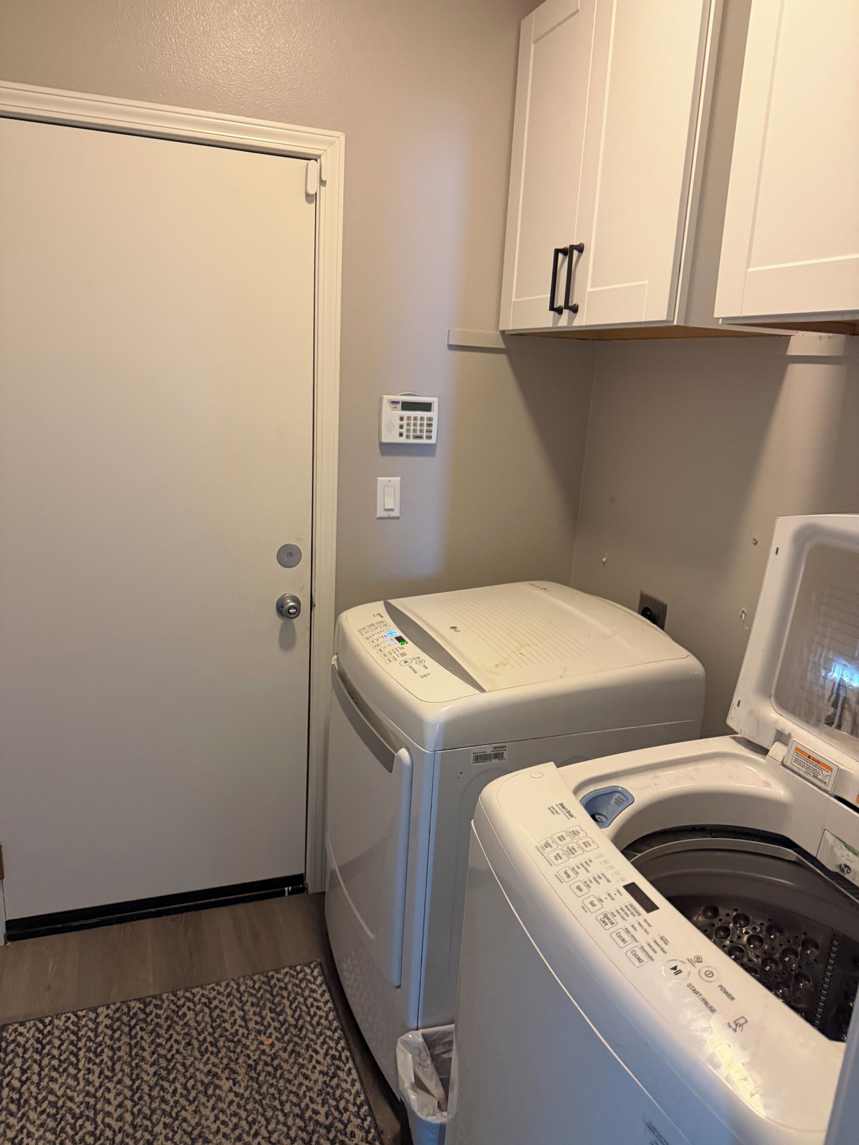 Une buanderie équipée d’un lave-linge et d’un sèche-linge à chargement frontal, d’un thermostat et d’une porte.