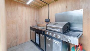 A compact kitchen with a built-in gas stove, a sink, and a stainless steel refrigerator.