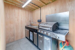 Cozinha compacta com fogão a gás embutido, pia e geladeira de aço inoxidável.