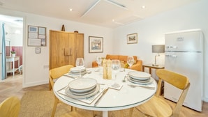 A dining area with a round glass table set for four, a wooden cabinet, and a white refrigerator. - 1 Bed in Stewarton (oc-c44699) (Stewarton)
