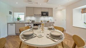 A modern kitchen with a dining area, equipped with a dishwasher, oven, and microwave. - 1 Bed in Stewarton (oc-c44699) (Stewarton)