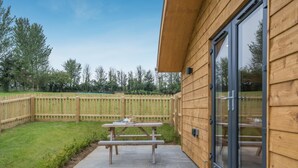 A wooden building with a patio, a picnic table, and a wooden fence. - 2 Bed in Adgestone (oc-i42801) (Brading)
