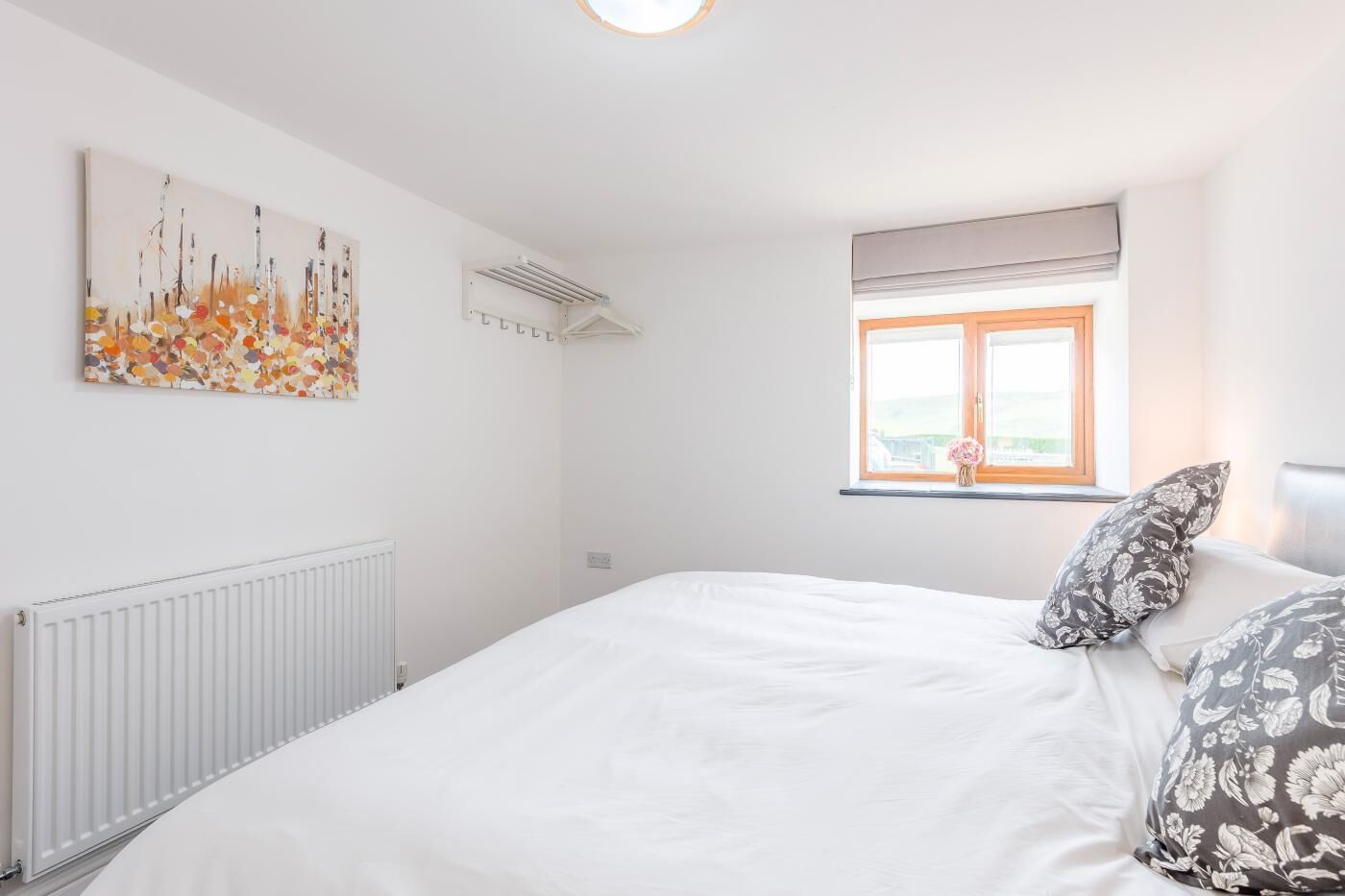 A bedroom with a large bed, a radiator, a window with a view, and a wall-mounted air conditioner.