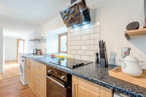 A modern kitchen with a granite countertop, stainless steel appliances, and a built-in oven. - 2 Bed in Rhoslefain (oc-u44707) (Rhoslefain)