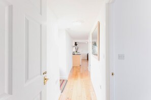 A hallway leading to a kitchen with a wooden floor and white walls. - 2 Bed in Rhoslefain (oc-u44707) (Rhoslefain)