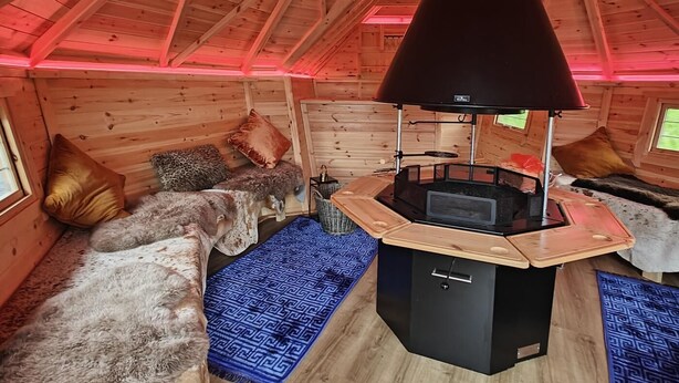 Ein gemütliches Blockhaus mit Kamin, Holzwänden und schrägem Dach.
