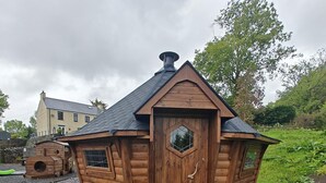 Eine Holzhütte mit Satteldach, einem Sechseckfenster und einem Schornstein.