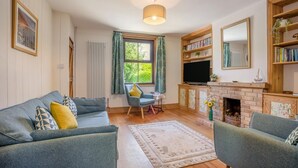 A living room with a sofa, armchair, fireplace, bookshelf, and a television. - 3 Bed in Studland (oc-o42812) (Studland)