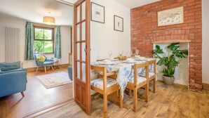A dining area with a brick wall, wooden table, and chairs. - 3 Bed in Studland (oc-o42812) (Studland)