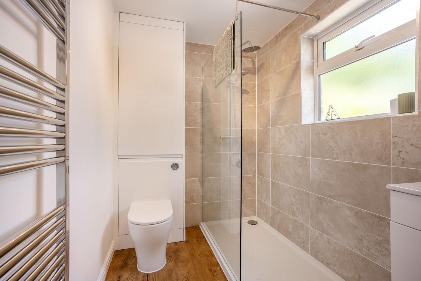 Une salle de bain avec une douche à parois de verre, des toilettes et une fenêtre.