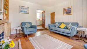 A living room with a blue sofa set, a small table, and a fireplace. - 3 Bed in Studland (oc-o42812) (Studland)