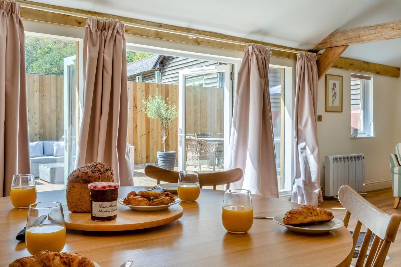 Una mesa de desayuno con cruasanes, pan y vasos de jugo de naranja.