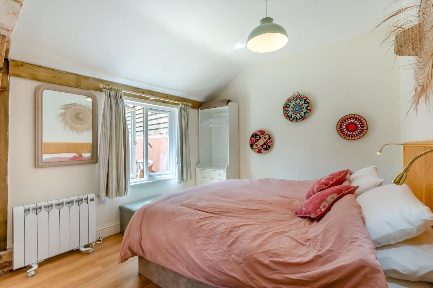Un dormitorio con cama, radiador, ventana con cortinas y adornos en la pared.