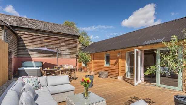 A wooden deck with a sofa, a table, and a hot tub. - 2 Bed in Hartest (oc-w42830) (Hartest)