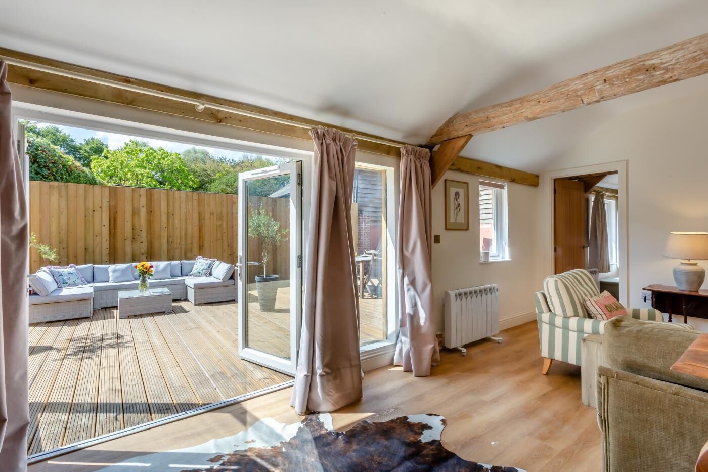 A spacious room with a wooden deck, a sofa set, a radiator, and a striped armchair.