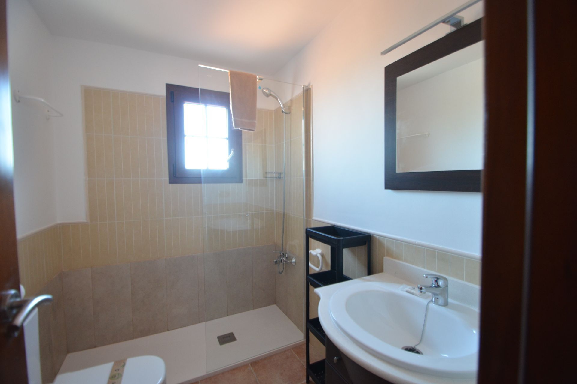 Ein Badezimmer mit Dusche, Toilette, Waschbecken und einem Fenster.