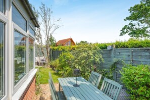 A backyard with a wooden table and chairs, a brick wall, and a wooden fence. - 2 Bed in Snettisham (oc-r42841) (Snettisham)
