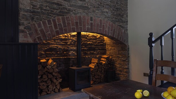 Ein rustikales Interieur mit Kamin aus Backstein, einem Holztisch mit Zitronen und einem Stuhl.