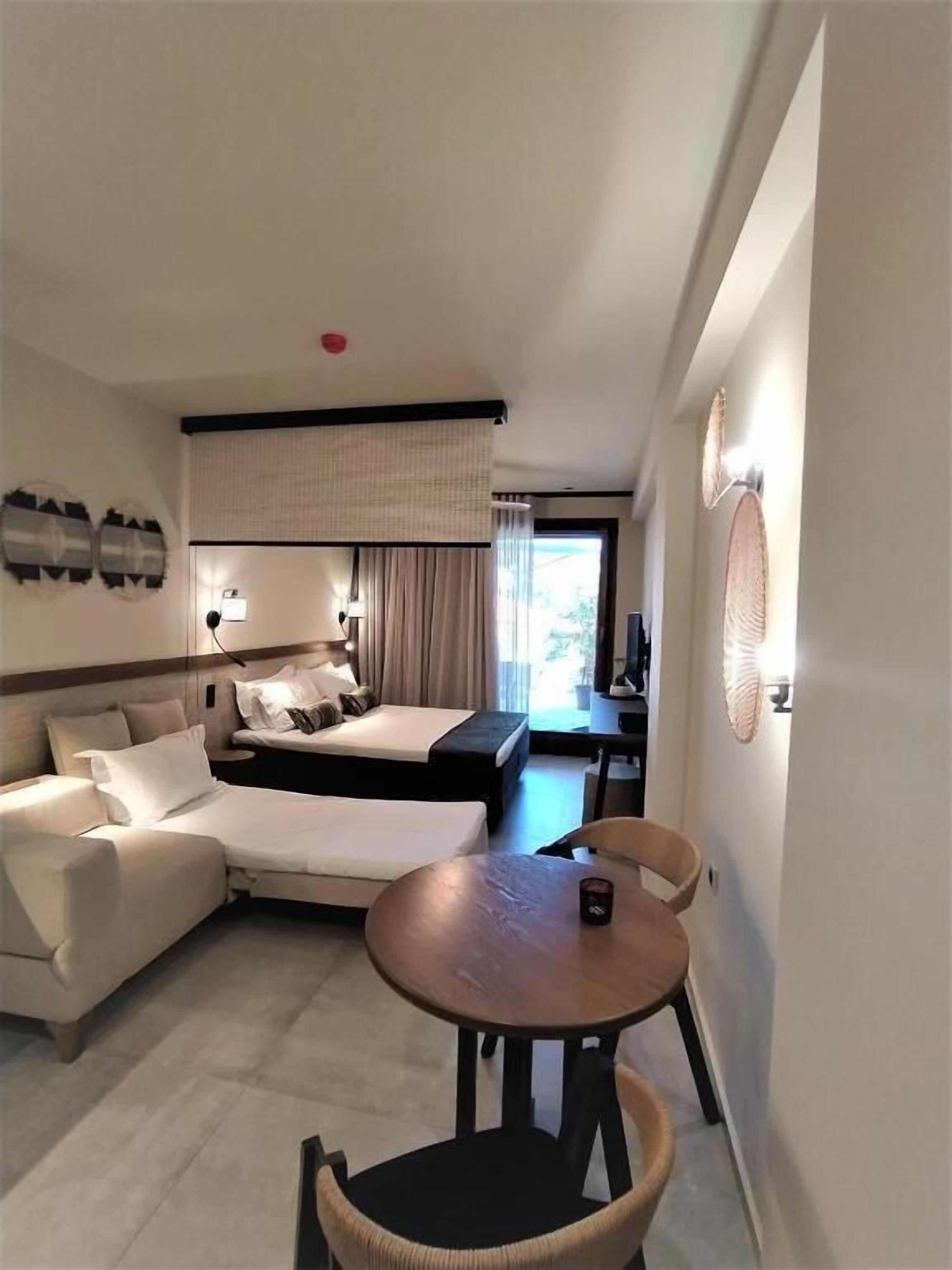 A hotel room with a sofa, a bed, a dining table, and a chair.