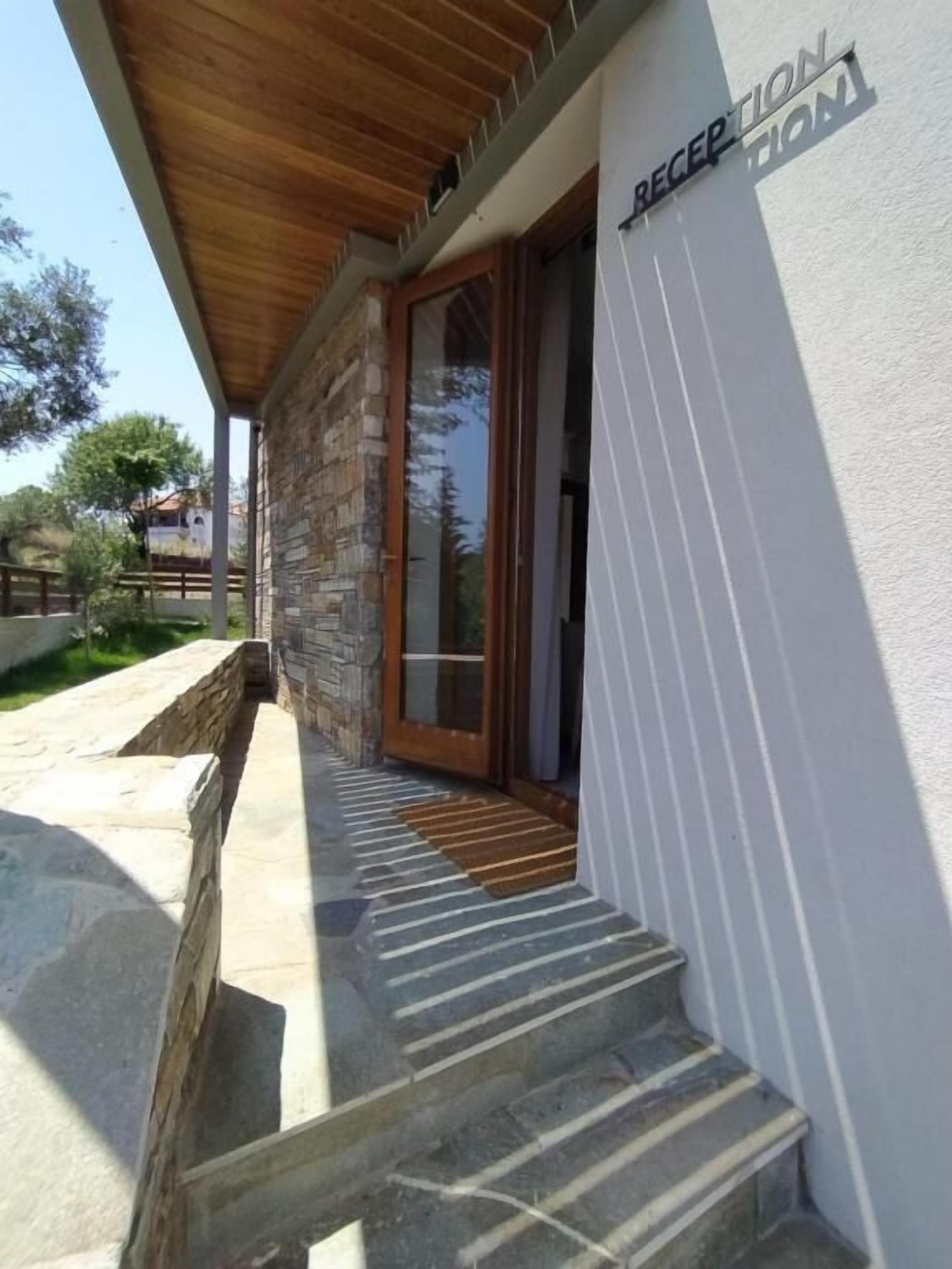 A stone building with a wooden overhang, a reception area, and a set of stone steps leading to a door.